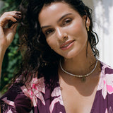 woman wearing dark purple playsuit with half sleeve, plunging neck line, pockets in an orchid print