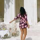 woman wearing dark purple playsuit with half sleeve, plunging neck line, pockets in an orchid print