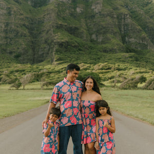 man wearing a nay button up aloha shirt with bright pink hibiscus print