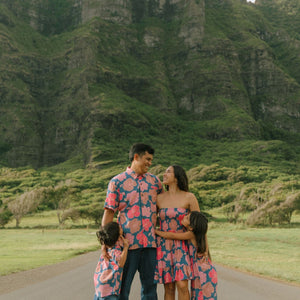 man wearing a nay button up aloha shirt with bright pink hibiscus print