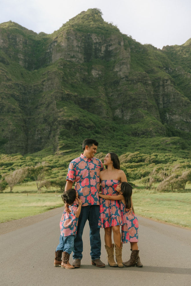 man wearing a nay button up aloha shirt with bright pink hibiscus print