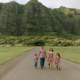 little boy wearing a nevy button up aloha shirt with bright pink hibiscus print