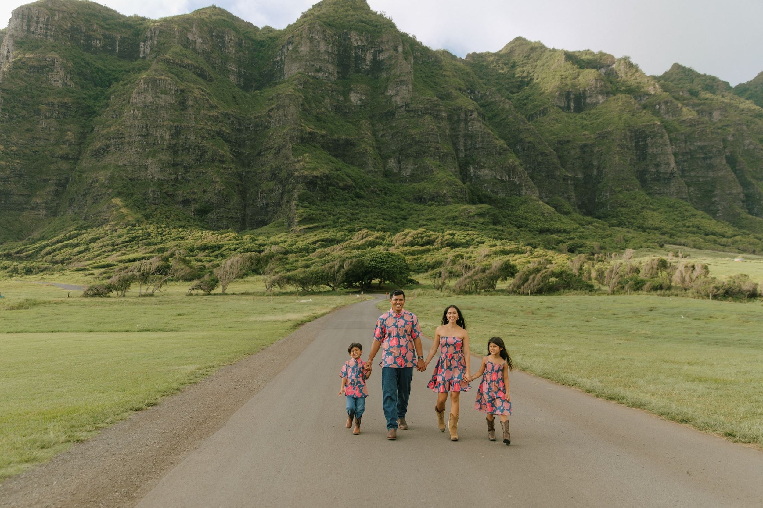 little boy wearing a nevy button up aloha shirt with bright pink hibiscus print