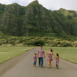 little girl wearing a navy spaghetti strap dress with bright pink hibiscus print