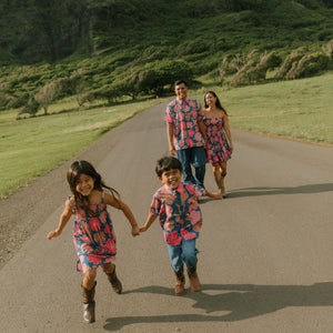 little girl wearing a navy spaghetti strap dress with bright pink hibiscus print