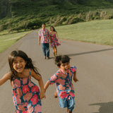 little boy wearing a nevy button up aloha shirt with bright pink hibiscus print