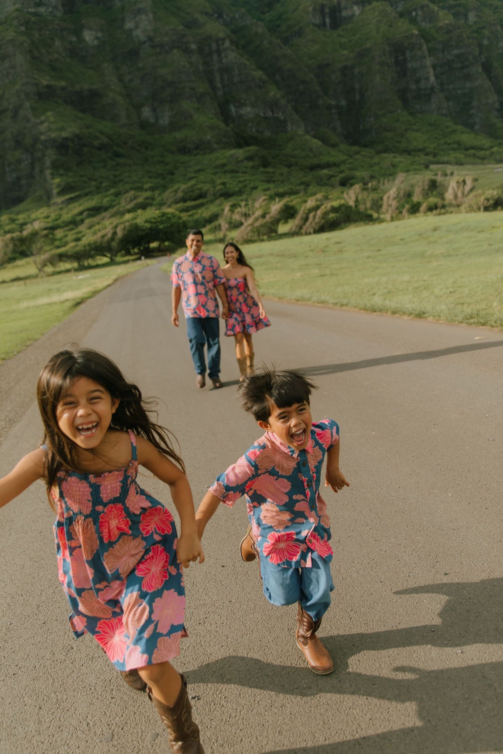 little boy wearing a nevy button up aloha shirt with bright pink hibiscus print