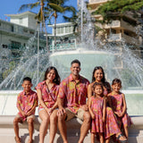 man wearing terracotta colored aloha shirt with large purple and yellow flower print