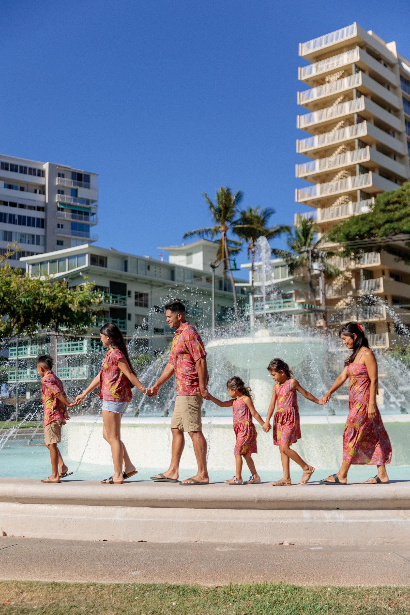 man wearing terracotta colored aloha shirt with large purple and yellow flower print