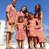 little girl wearing terracotta colored high neck sleeveless knee length dress with large purple and yellow flower print
