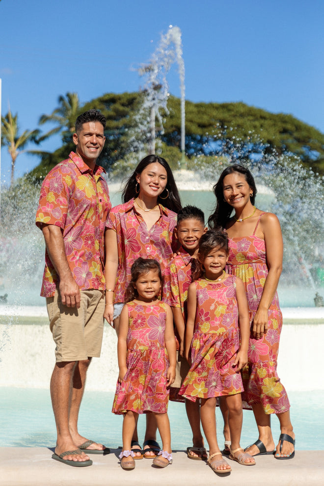man wearing terracotta colored aloha shirt with large purple and yellow flower print
