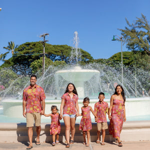little boy wearing terracotta colored aloha shirt with large purple and yellow flower print 