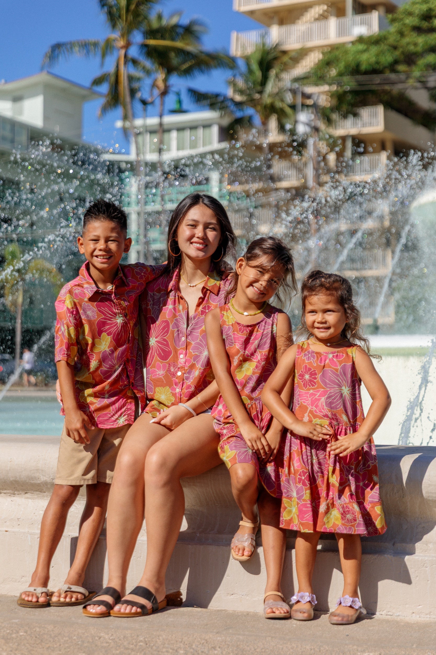 little boy wearing terracotta colored aloha shirt with large purple and yellow flower print 