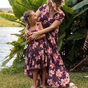 little girl wearing dark purple dress with flutter sleeve and orchid print