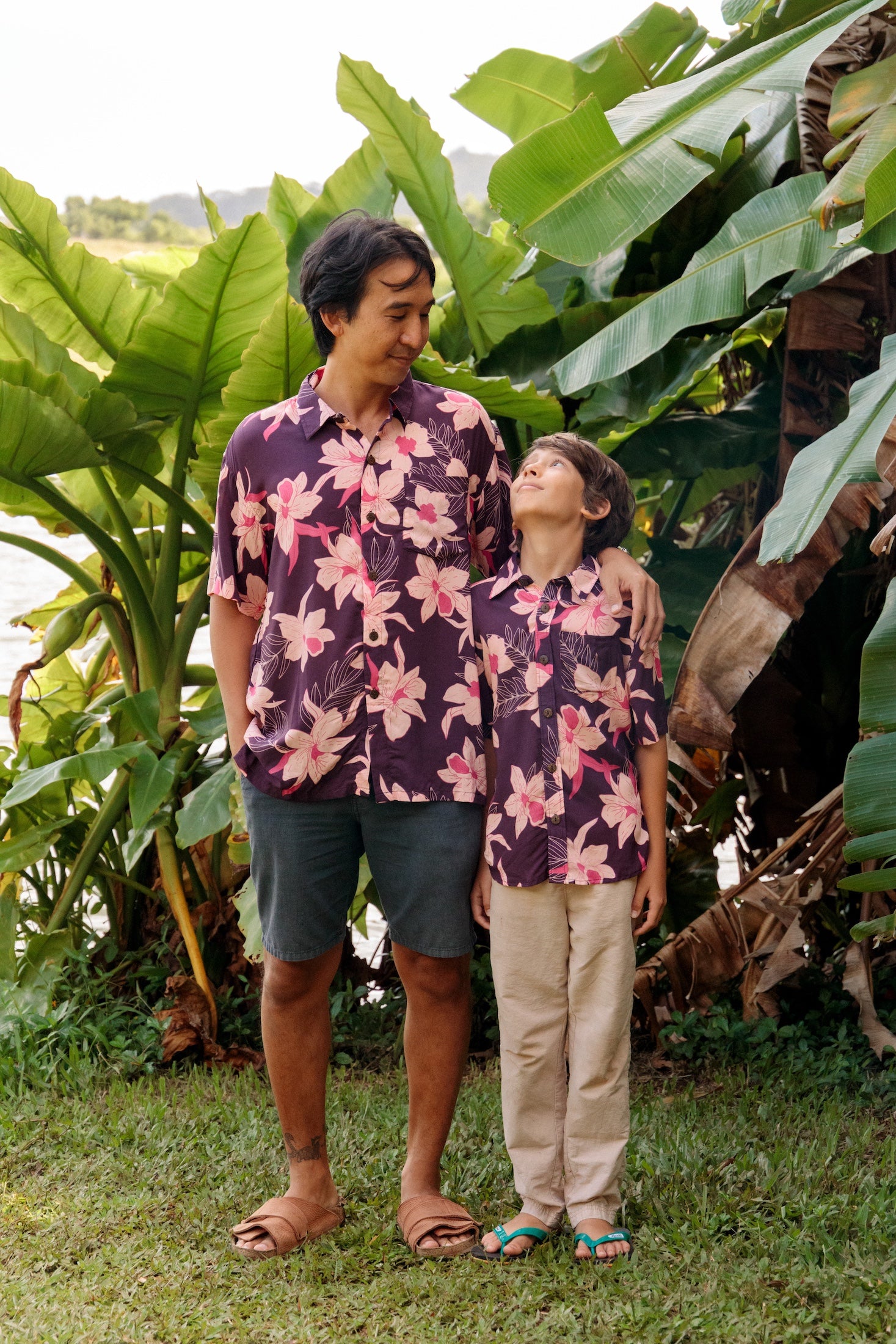 little boy wearing a dark purple aloha button up shirt with orchid print