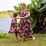 little girl wearing dark purple dress with flutter sleeve and orchid print