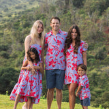 man with brown hair wearing a button up aloha shirt with periwinkle background and bright red hibiscus print.