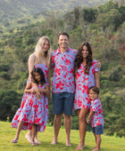 man with brown hair wearing a button up aloha shirt with periwinkle background and bright red hibiscus print.