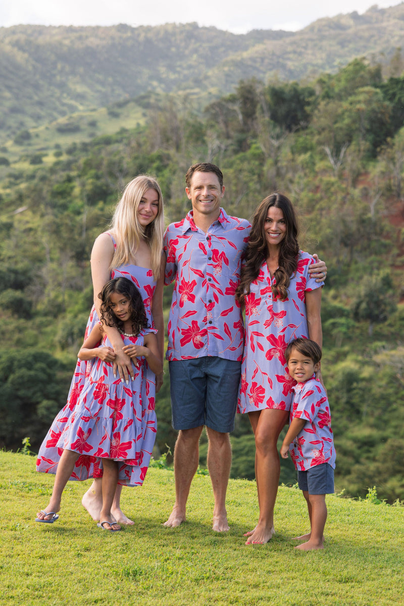 man with brown hair wearing a button up aloha shirt with periwinkle background and bright red hibiscus print.