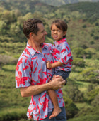 man with brown hair wearing a button up aloha shirt with periwinkle background and bright red hibiscus print.