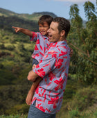 man with brown hair wearing a button up aloha shirt with periwinkle background and bright red hibiscus print.