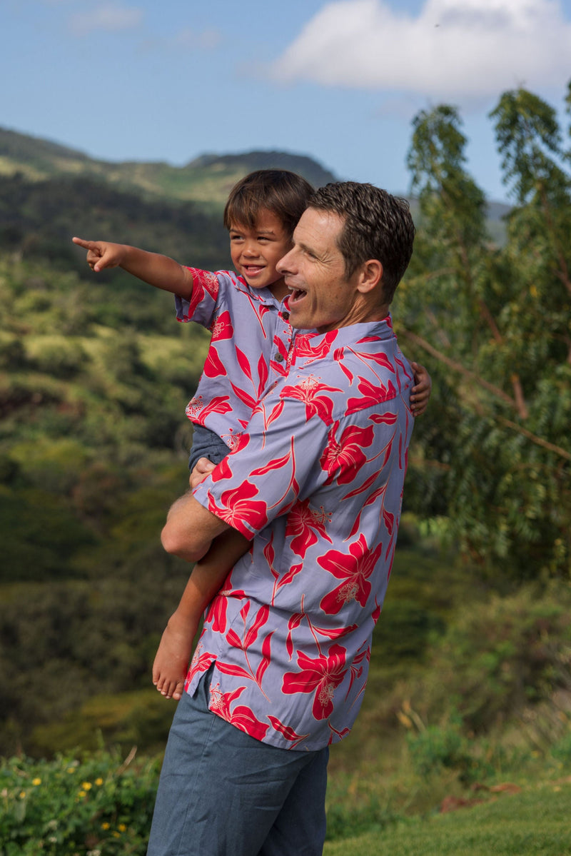 man with brown hair wearing a button up aloha shirt with periwinkle background and bright red hibiscus print.