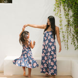 little girl wearing a tiered maxi dress in navy and pink hibiscus print.