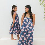 little girl wearing a tiered maxi dress in navy and pink hibiscus print.