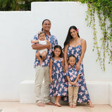 little boy wearing button up aloha shirt in navy and pink hibiscus print.