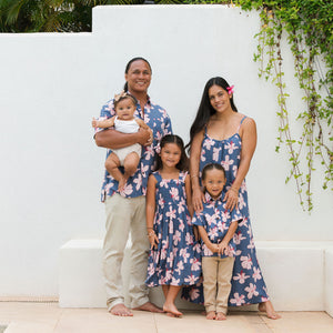 little boy wearing button up aloha shirt in navy and pink hibiscus print.