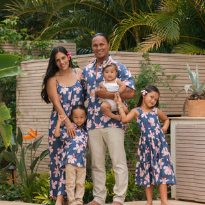 man wearing button up aloha shirt in navy and pink hibiscus print.