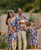 man wearing button up aloha shirt in navy and pink hibiscus print.