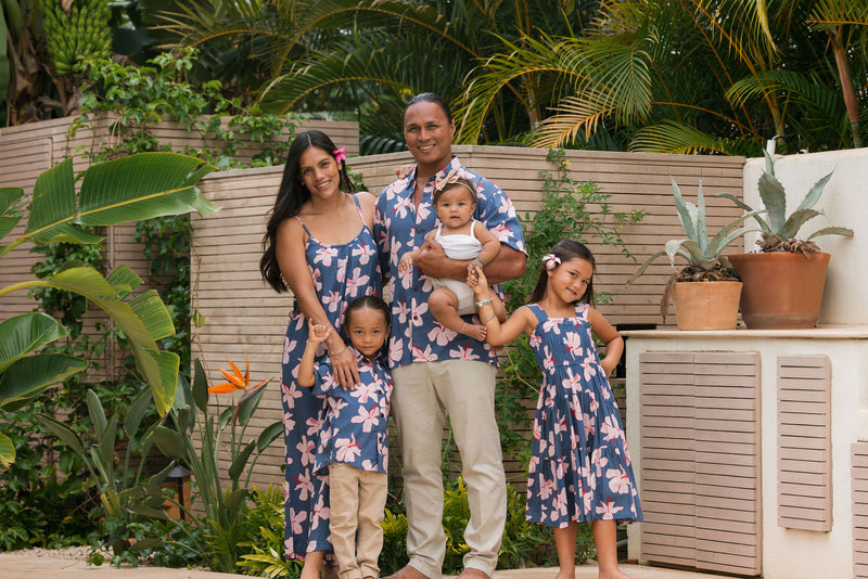 man wearing button up aloha shirt in navy and pink hibiscus print.