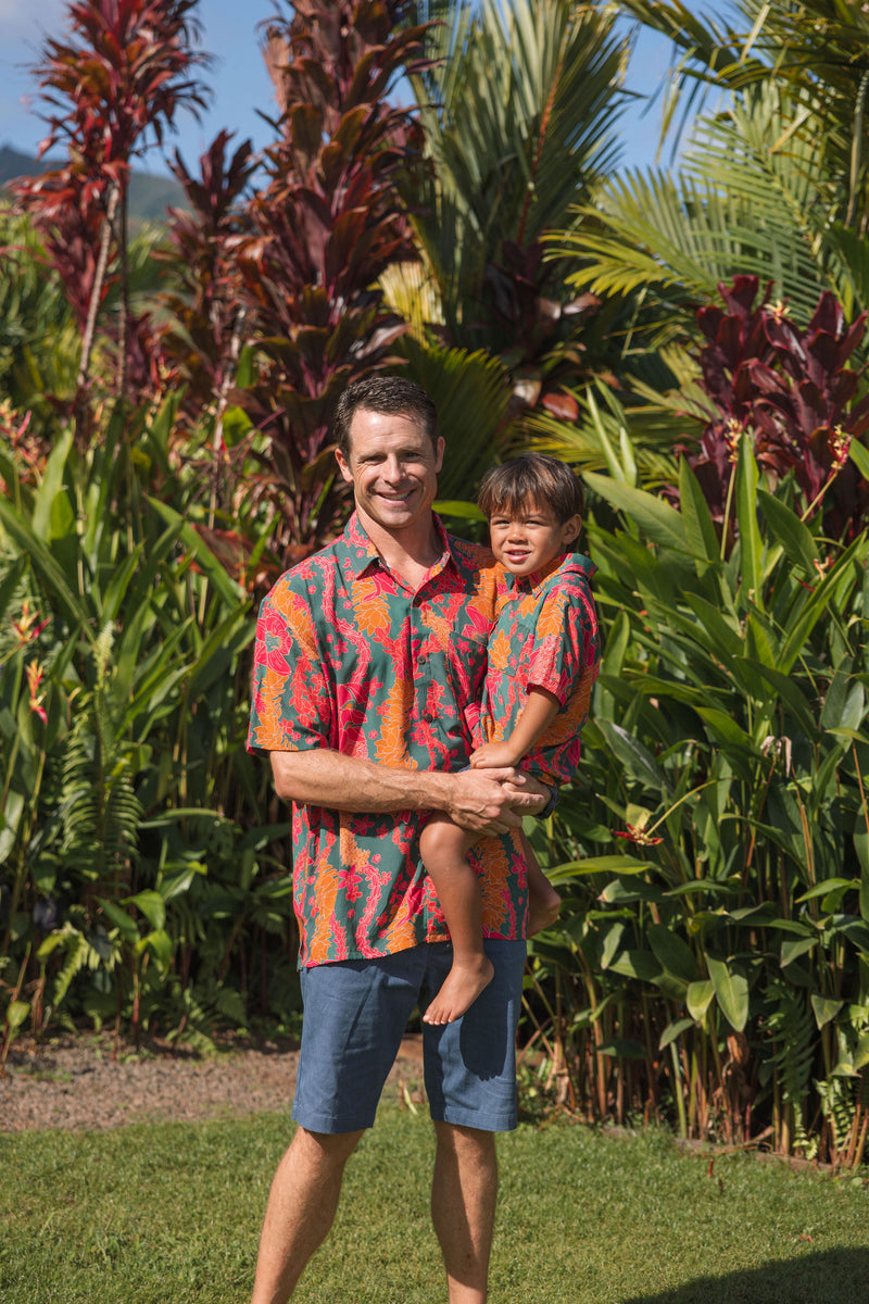 man with brown hair wearing a colorful button up aloha shirt with tropical lei print