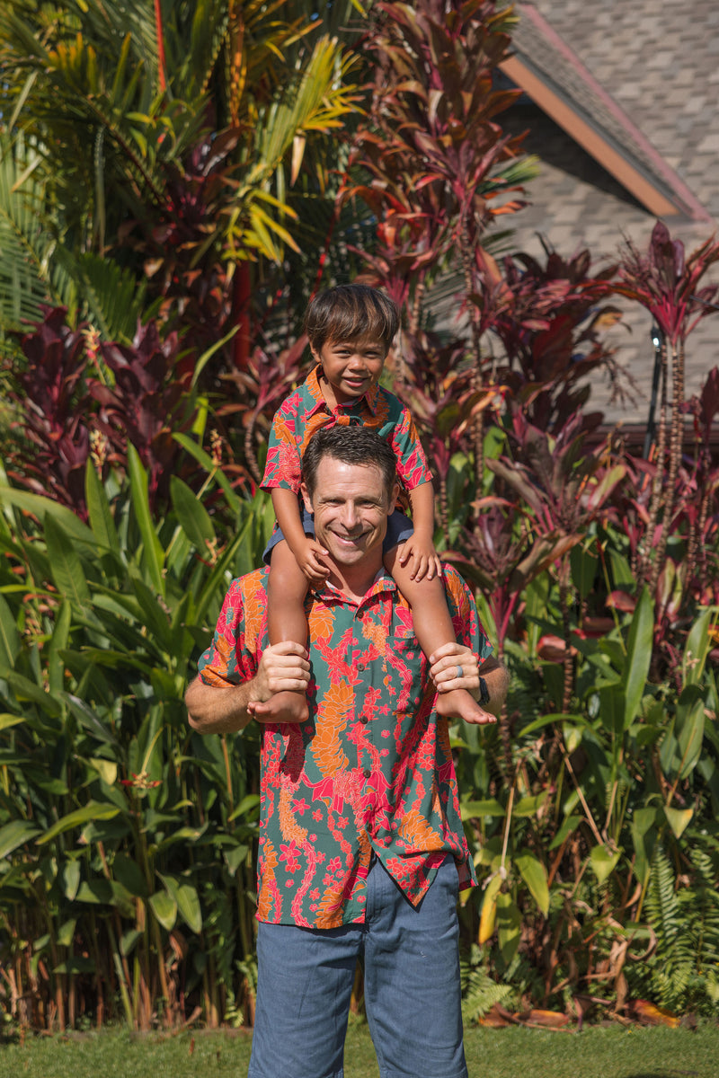 man with brown hair wearing a colorful button up aloha shirt with tropical lei print
