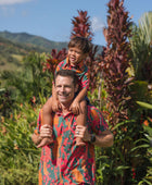 man with brown hair wearing a colorful button up aloha shirt with tropical lei print