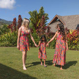 girl with brown hair wearing a colorful dress with tropical lei print