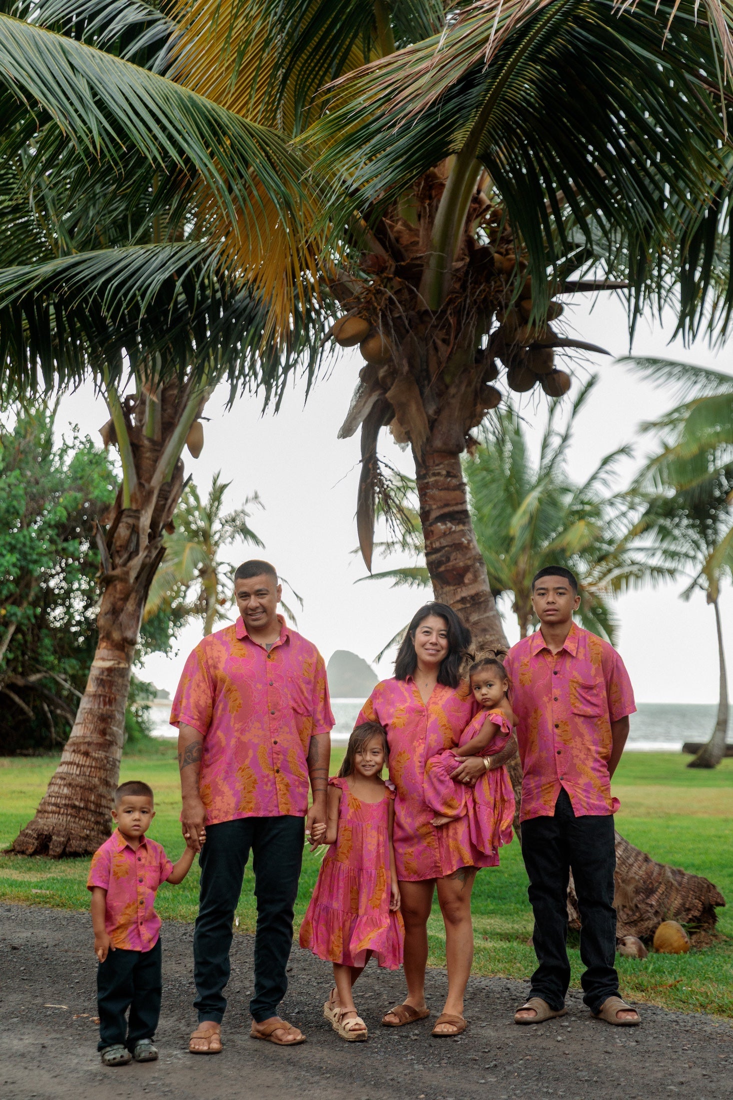 family wearing matching pink aloha wear with lei print