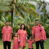 family wearing matching pink aloha wear with lei print