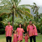 family wearing matching pink aloha wear with lei print