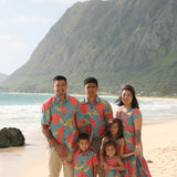 little boy wearing a green button up shirt with orange and yellow lei pua print