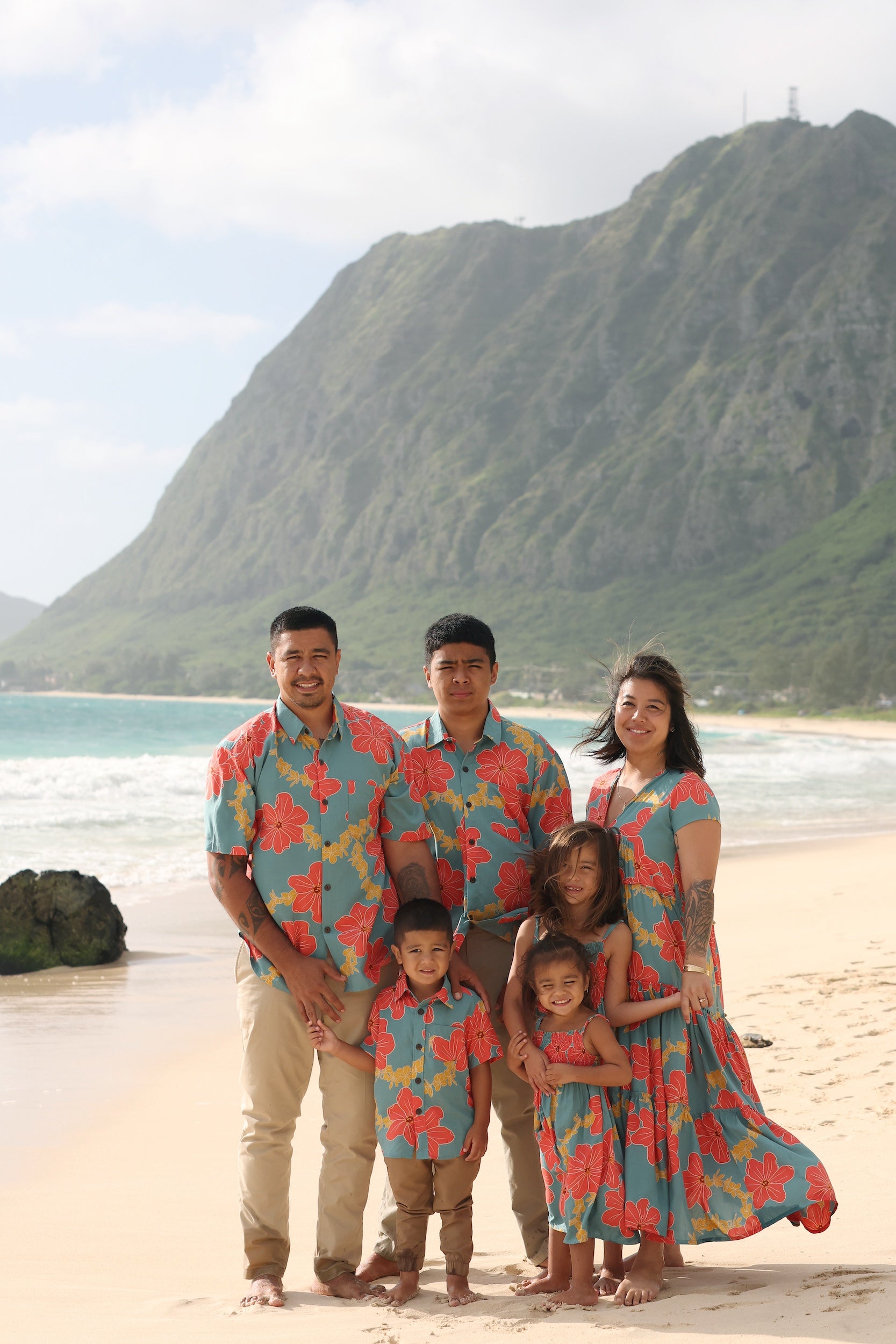 little boy wearing a green button up shirt with orange and yellow lei pua print