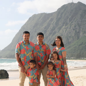 man wearing green button up shirt with orange and yellow lei pua print