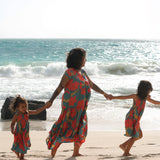 little girl wearing a green knee length dress with orange and yellow lei pua print 