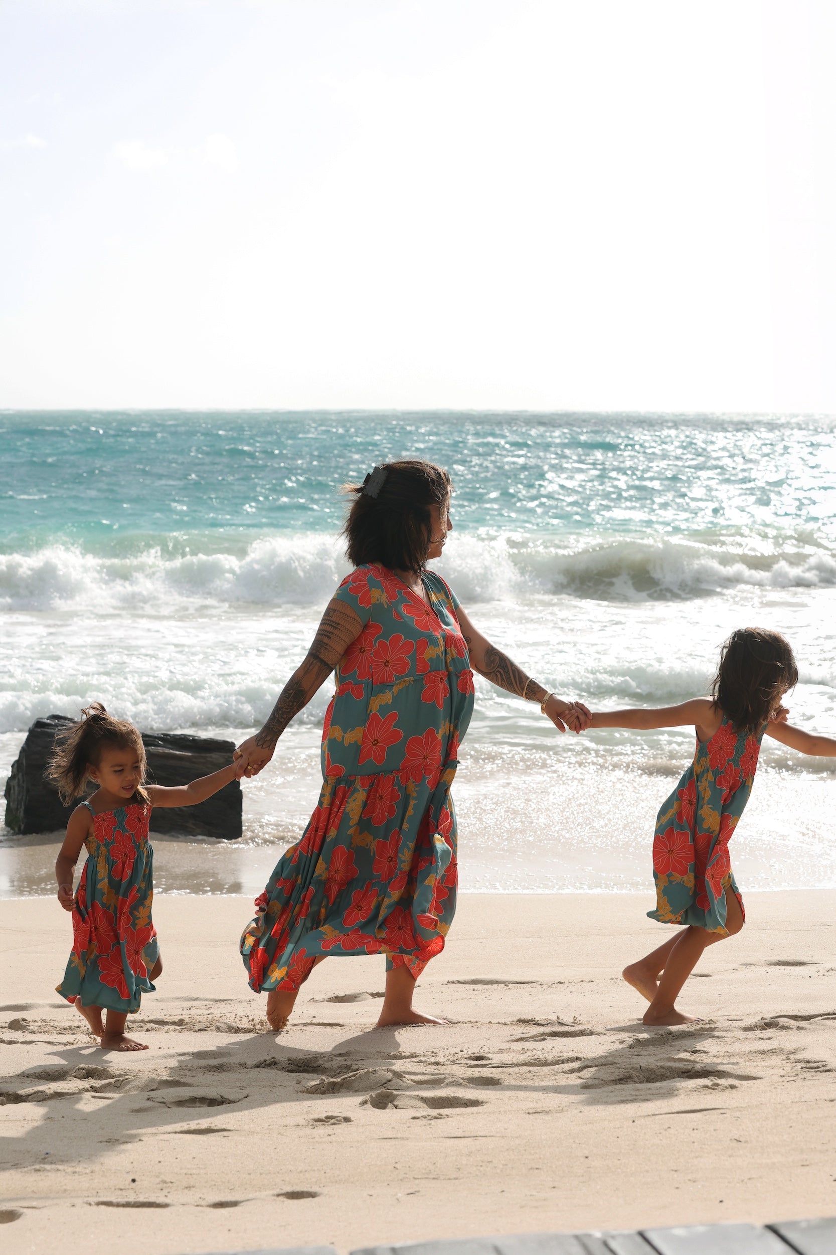 little girl wearing a green knee length dress with orange and yellow lei pua print 