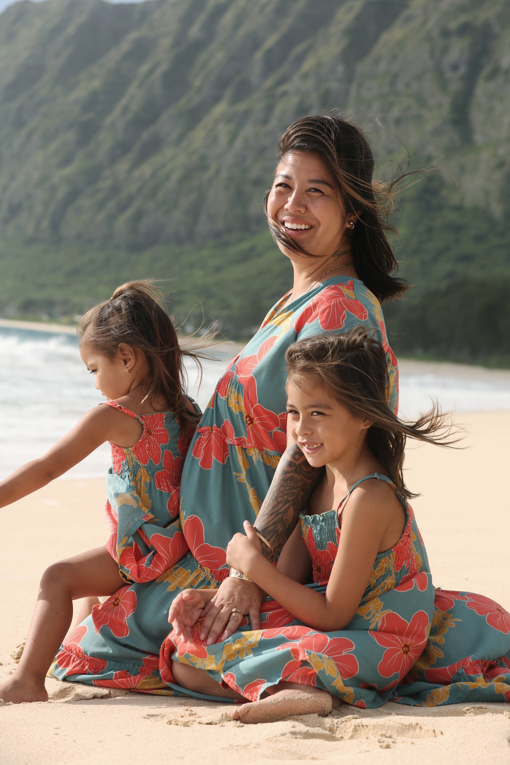 little girl wearing a green knee length dress with orange and yellow lei pua print 