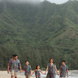 little boy wearing aloha button up shirt in dark teal with shell and lei print