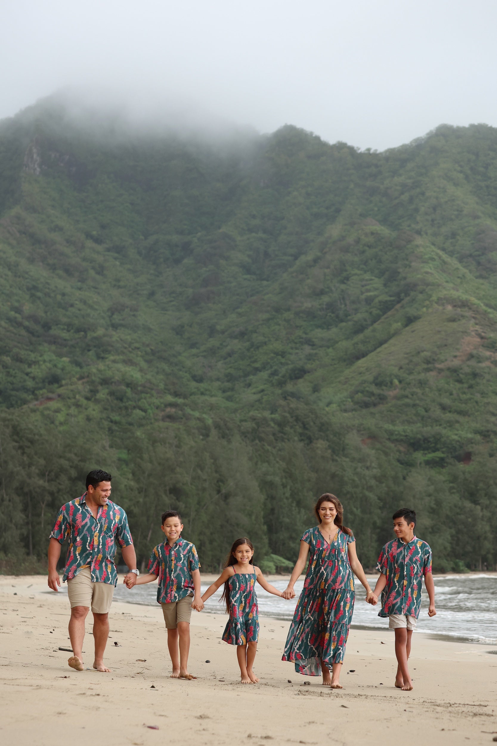 little boy wearing aloha button up shirt in dark teal with shell and lei print