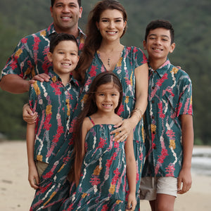 little girl wearing a knee length dress with tie spaghetti straps in dark teal with shell and lei print