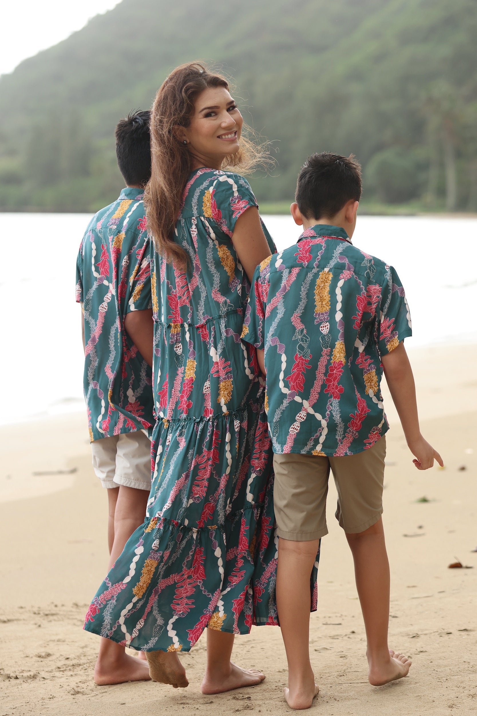 little boy wearing aloha button up shirt in dark teal with shell and lei print